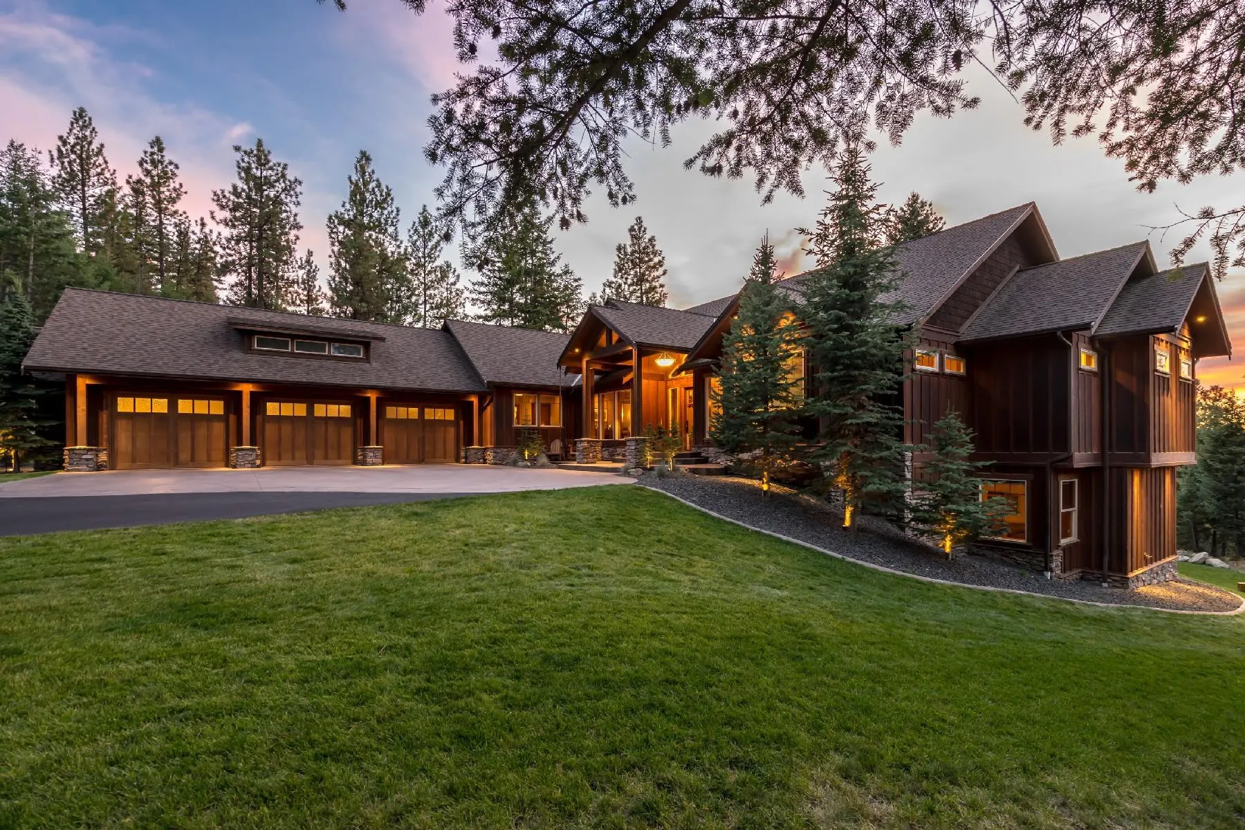 Large custom craftsman home showing garage and main house at twilight with exterior lights on Coeur d'Alene ID